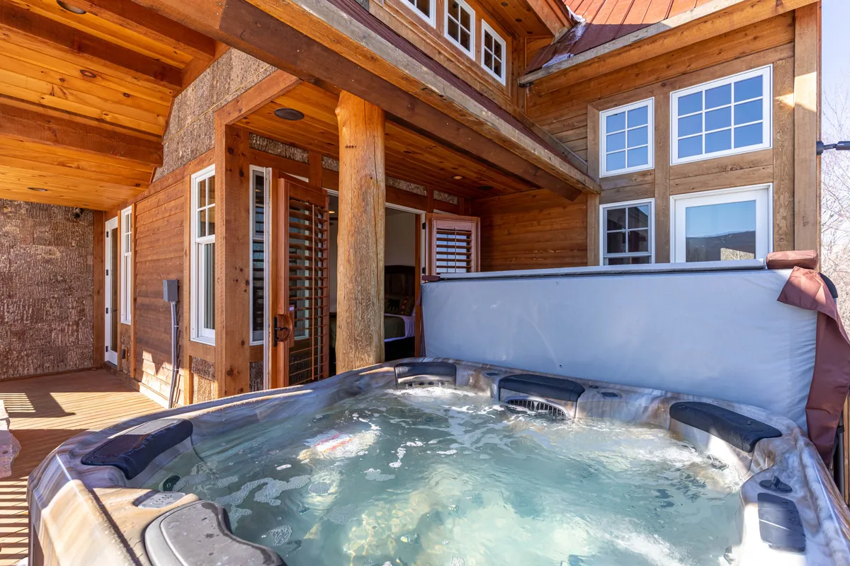 A tranquil outdoor deck with a hot tub, wooden decking, and the warm tones of the home’s exterior. The space is clearly designed for relaxation and socializing, offering opportunities for both group fun and private unwinding.
